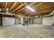 Unfinished basement with exposed wood ceiling, concrete floor, and potential for customization with garage door access at 5010 Highway 20 Ne, Conyers, GA 30012