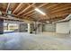 Unfinished basement with exposed wood ceiling, concrete floor, sink, and garage door leading outside to the lake at 5010 Highway 20 Ne, Conyers, GA 30012