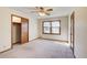 A carpeted bedroom with trim detail, a ceiling fan, closet, and a large window provides lots of light at 5010 Highway 20 Ne, Conyers, GA 30012
