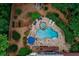 Aerial view of a backyard oasis with a freeform pool, hot tub, stone patio, and lush landscaping surrounded by green trees at 5053 Chapel Xing, Douglasville, GA 30135