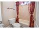 Bathroom featuring a white toilet and tub/shower combo with tile surround and burgundy shower curtains at 5053 Chapel Xing, Douglasville, GA 30135