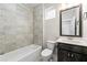 Well-lit bathroom with a shower/tub combo, gray tiled walls, and a dark wood vanity at 513 Broadview Ln, Atlanta, GA 30324