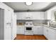 Traditional-style kitchen featuring white cabinetry, updated appliances, and warm wood flooring at 3016 Ansley Manor Ct, Snellville, GA 30078