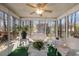 Enclosed sunroom has tiled floor and wicker furniture with views of wooded backyard at 3016 Ansley Manor Ct, Snellville, GA 30078