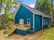 A side view of a teal home featuring a new deck with stairs, and lush, green surroundings at 1321 Bridges Sw Ave, Atlanta, GA 30310