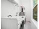 Bright laundry room featuring modern front-load washer and dryer, storage shelves, and crisp white walls at 1321 Bridges Sw Ave, Atlanta, GA 30310