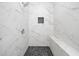 Modern shower featuring sleek white tile walls, a built-in bench, and pebble tile floor at 1321 Bridges Sw Ave, Atlanta, GA 30310
