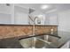 Close-up of a kitchen sink featuring granite countertops and a tile backsplash at 2393 Strand Ave, Lawrenceville, GA 30043
