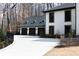 A three car garage with dark doors and light concrete driveway, stone accents, and an attached white home at 3565 Haddon Hall Nw Rd, Atlanta, GA 30327