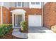 Townhome exterior featuring a one-car garage, manicured bushes, and covered entrance at 4000 Howell Park Rd, Duluth, GA 30096