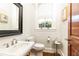 Well-lit powder room featuring a pedestal sink, a dark framed mirror, and a window at 57 Rumson Ne Way, Atlanta, GA 30305