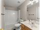 Well-lit bathroom features a shower-tub combo, bright white tile, and wood cabinets at 2405 Landrum Ct, Lawrenceville, GA 30043