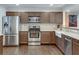 Well-lit kitchen featuring stainless steel appliances and wood cabinets with tiled backsplash and hardwood flooring at 2031 Audubon Ne Dr, Atlanta, GA 30329