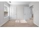 Neutral bedroom with carpet and white trim, featuring a window and doors that bring in natural light at 1558 Autumn Wood Trl, Sugar Hill, GA 30518