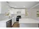 Bright white kitchen featuring modern appliances, quartz countertops, island, and hardwood floors at 1506 Sycamore Nw Dr, Kennesaw, GA 30152