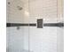 Close-up of white tiled shower with glass door and decorative accent tile at 1506 Sycamore Nw Dr, Kennesaw, GA 30152