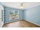 Bright bedroom featuring laminate flooring, light blue walls, a ceiling fan, and outside greenery views at 172 Shallow Ridge Ne Ln, Kennesaw, GA 30144