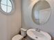 This bathroom features an oval mirror, a sink, and a toilet, with a unique round window for added charm at 4498 Dunblane Ave, Sugar Hill, GA 30518