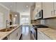 Well-lit kitchen featuring stainless steel appliances, granite countertops, and a kitchen island with a sink and faucet at 4498 Dunblane Ave, Sugar Hill, GA 30518