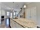 Beautiful kitchen island with granite countertops, stainless steel sink and faucet, and a view of the living room at 4498 Dunblane Ave, Sugar Hill, GA 30518