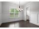 Bright dining room with hardwood floors, natural light, wainscoting, modern chandelier, and a side view of a wet bar at 628 Avondale Hills Dr, Decatur, GA 30032