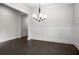 Empty dining room with hardwood floors, wainscoting, a modern chandelier, and large windows for ample light at 628 Avondale Hills Dr, Decatur, GA 30032