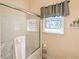 This bathroom features a tiled shower with a glass door, a window, and a neutral color palette at 2520 Cross Springs Dr, Cumming, GA 30041