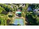 An aerial view showcasing a community pool, tennis courts, and homes nestled amidst lush green trees and a small lake at 6560 Waveland Dr, Cumming, GA 30040