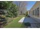 A serene backyard showing a concrete patio and a well-maintained lawn surrounded by trees and manicured landscaping at 6560 Waveland Dr, Cumming, GA 30040