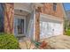 View of the front entrance and garage of a brick home, enhanced by stylish exterior lighting at 6560 Waveland Dr, Cumming, GA 30040