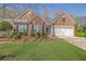 Charming brick home with a well-manicured lawn, beautiful landscaping, and an attached two-car garage at 6560 Waveland Dr, Cumming, GA 30040