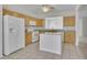 Well-lit kitchen with white appliances, tile flooring, and granite countertops with an island and wooden cabinets at 6560 Waveland Dr, Cumming, GA 30040