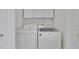 Efficient laundry room with white washer, dryer, and overhead cabinets at 6560 Waveland Dr, Cumming, GA 30040