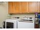 Laundry room featuring modern white washer and dryer beneath oak cabinets at 1439 Evers Pl, Lawrenceville, GA 30043