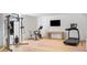 Home gym featuring hardwood floors, stationary bike, weight training station, treadmill, and mounted TV at 14 Lake Forrest Ln, Atlanta, GA 30342