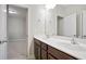 Bathroom featuring a double sink vanity with brown cabinets and view into connecting room at 2471 Arnold Palmer Way, Duluth, GA 30096