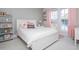 Bright bedroom with a white bed frame, pink accents, and shelving with decorative items near the window at 385 Rowes Cir, Alpharetta, GA 30009
