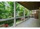 Covered porch with wooden floors, railing and comfortable seating overlooking a well-manicured yard at 385 Rowes Cir, Alpharetta, GA 30009