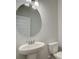 Elegant powder room with a pedestal sink, round mirror, and efficient toilet at 4594 Eastbrook Pl, Snellville, GA 30039