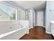 Bright bathroom with tiled tub, separate shower, and wood-look flooring at 1761 Brandemere Dr, Austell, GA 30168