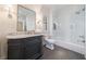 Modern bathroom featuring a gray vanity, marble countertop, and tub-shower combo with a glass door at 479 Argonne Nw Dr, Atlanta, GA 30305