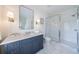 Well-lit bathroom with marble countertop, blue vanity, and glass-enclosed shower with white subway tile surround at 479 Argonne Nw Dr, Atlanta, GA 30305