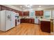 Well-lit kitchen with wooden cabinets, hardwood floors, and modern white appliances for a functional cooking space at 2208 Clarendon Ne Ct, Conyers, GA 30012