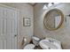 Classic powder room featuring a round mirror, pedestal sink, and decorative wall art at 4260 River Club Dr, Cumming, GA 30041