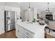 Modern kitchen island with white countertop, stainless steel refrigerator, and view into living room at 3387 Wild Clary Court Lot 20, Buford, GA 30519