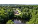 An aerial view shows a home near a pond surrounded by trees in a neighborhood, with a backyard fire pit at 144 Bobs Sw Dr, Mableton, GA 30126