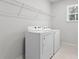 Bright laundry room with white washer, dryer, wire shelving, and natural light from a window at 3479 Jasmine Sw Way, Atlanta, GA 30331