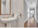 Elegant powder room with pedestal sink, gold fixtures, and bamboo-framed mirror adds a touch of luxury at 1139 Tennyson Ne Pl, Brookhaven, GA 30319