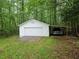 Exterior shot of a detached garage with a truck parked in an attached shelter surrounded by trees at 147 Mildred Ct, Dallas, GA 30157