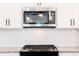 Close-up of microwave with white cabinets, granite countertops, and subway tile backsplash at 121 Priestwood Ln, Acworth, GA 30102